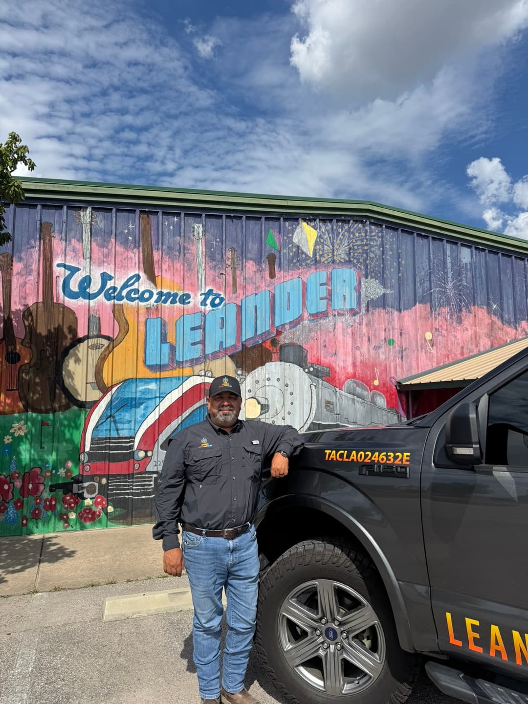 Lee Ortiz standing with his Leander Heating & Cooling service truck